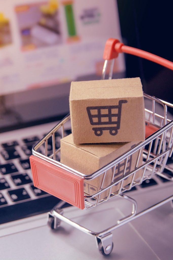 Parcel-filled toy shopping trolley standing on a laptop