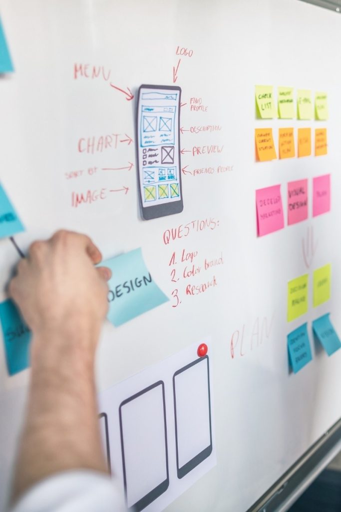 Phone interface wireframe beside notes being placed by hand
